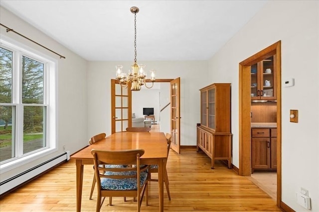dining area featuring a chandelier, a baseboard heating unit, french doors, and light wood-type flooring