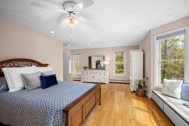 bedroom featuring a ceiling fan, baseboard heating, and light wood-type flooring