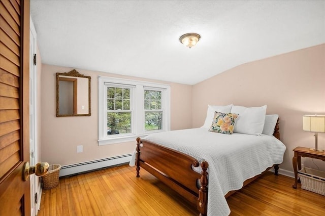 bedroom featuring light wood-style floors, baseboards, a baseboard radiator, and lofted ceiling