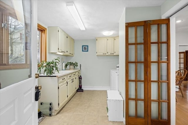 laundry area with cabinet space, washing machine and clothes dryer, french doors, baseboards, and light tile patterned floors