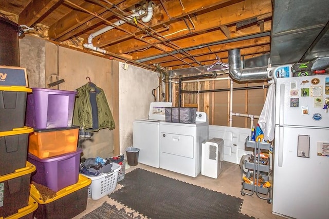 basement featuring washing machine and clothes dryer and white refrigerator