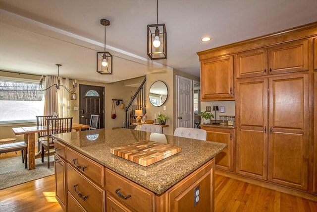 kitchen with pendant lighting, dark stone counters, a center island, and light wood-type flooring