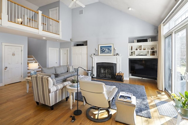 living room with ceiling fan, high vaulted ceiling, and light wood-type flooring