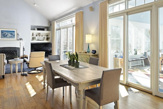 dining area with high vaulted ceiling, light hardwood / wood-style floors, and a wealth of natural light