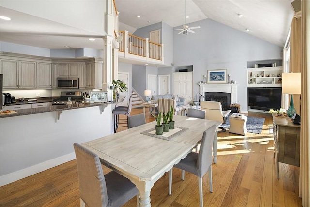 dining room featuring ceiling fan, high vaulted ceiling, and light hardwood / wood-style floors