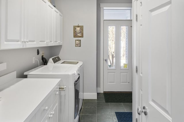 clothes washing area with washer and dryer, dark tile patterned flooring, and cabinets