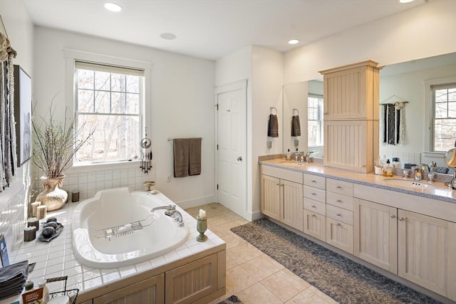 bathroom with tiled tub, vanity, and tile patterned floors