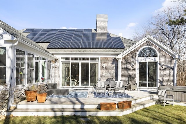 back of house featuring a hot tub, solar panels, and a deck