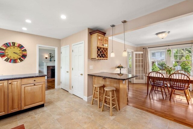43 Chilton St, Belmont, MA 02478 - kitchen with a peninsula, a kitchen bar, baseboards, decorative light fixtures, and a brick fireplace
