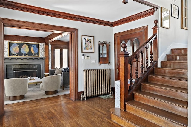 9 Prospect St, Winchester, MA 01890 - foyer entrance featuring radiator heating unit, stairs, dark wood-style flooring, a fireplace, and crown molding