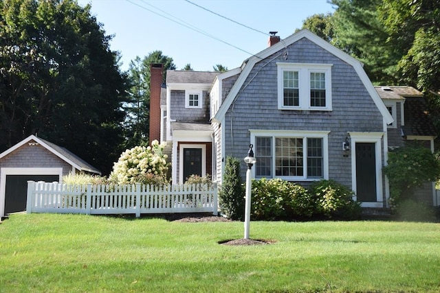 view of front of property with fence, a gambrel roof, a chimney, a front lawn, and a garage