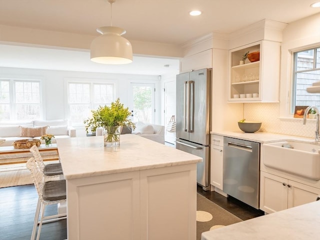 kitchen featuring dark wood-type flooring, a breakfast bar, a sink, appliances with stainless steel finishes, and decorative backsplash