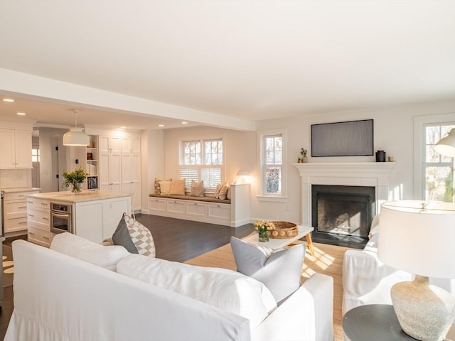 living area with a fireplace with flush hearth, dark wood-style floors, recessed lighting, and a wealth of natural light