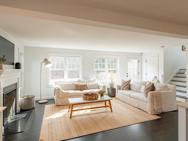 living area with stairway, baseboards, dark wood finished floors, and a fireplace