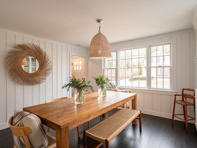 dining space featuring a decorative wall and dark wood-style flooring