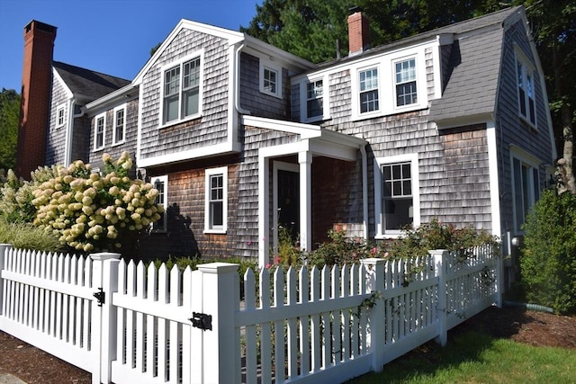 view of front of property with a fenced front yard, a garage, roof with shingles, and a chimney