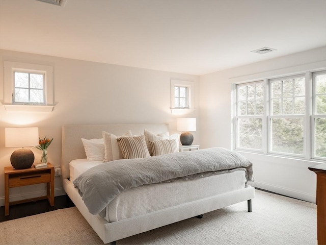 bedroom with visible vents, baseboards, and wood finished floors