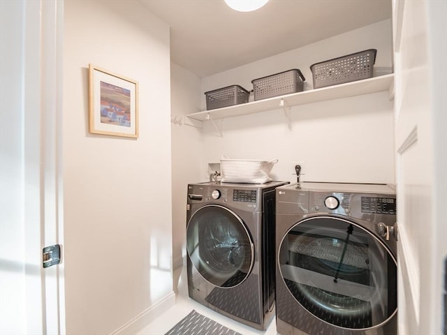 clothes washing area with baseboards, laundry area, and washer and clothes dryer