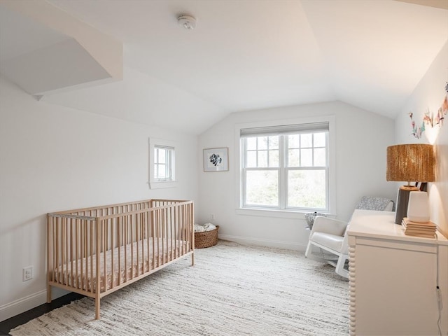 bedroom with lofted ceiling, a nursery area, and baseboards