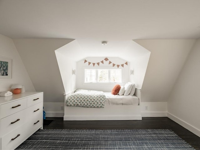 bedroom with baseboards, lofted ceiling, and dark wood-style flooring