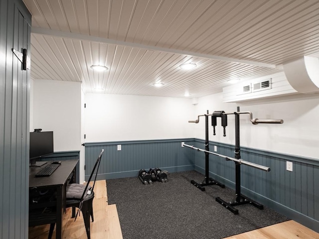 workout room with a wainscoted wall and wood ceiling