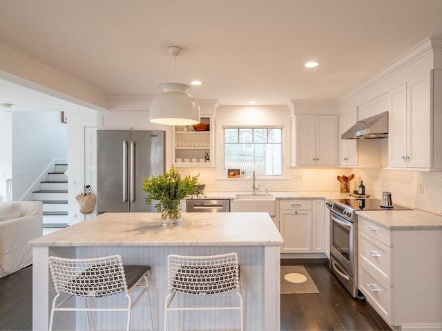 kitchen with extractor fan, a breakfast bar area, appliances with stainless steel finishes, dark wood-style floors, and white cabinets