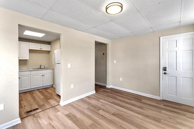 34 Worcester Rd, Charlton, MA 01507 - kitchen featuring freestanding refrigerator, a drop ceiling, white cabinetry, light wood-style floors, and a sink