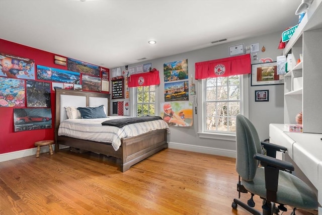 bedroom with visible vents, multiple windows, and light wood-style flooring