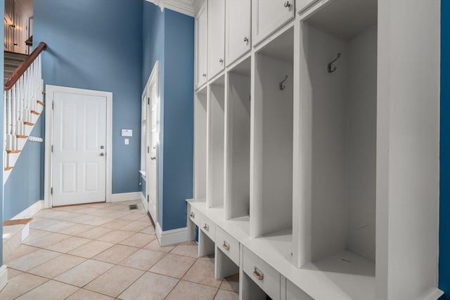 mudroom with light tile patterned flooring, baseboards, and a towering ceiling