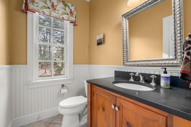 bathroom with tile patterned flooring, wainscoting, toilet, and vanity