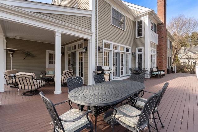 wooden terrace with outdoor dining space, french doors, and a grill