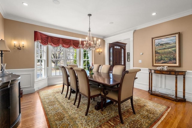 dining space with wood finished floors, recessed lighting, ornamental molding, wainscoting, and a chandelier