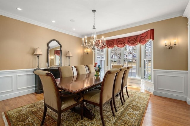 dining room featuring a chandelier, a wainscoted wall, and light wood-style floors