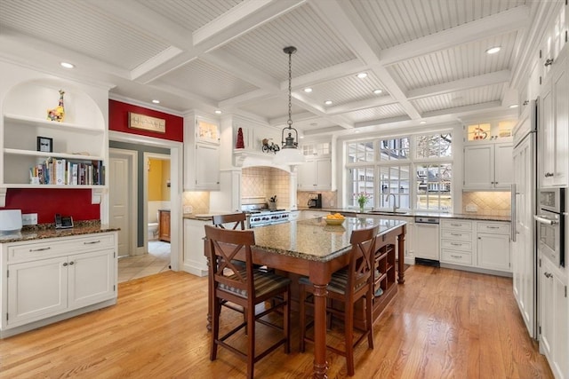 dining area with beamed ceiling, coffered ceiling, and light wood-style flooring