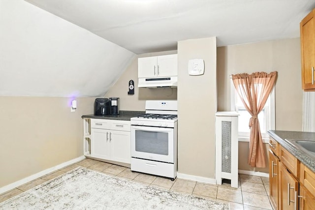 52 Harvard St, Chicopee, MA 01020 - kitchen featuring white gas stove, under cabinet range hood, light tile patterned floors, baseboards, and vaulted ceiling