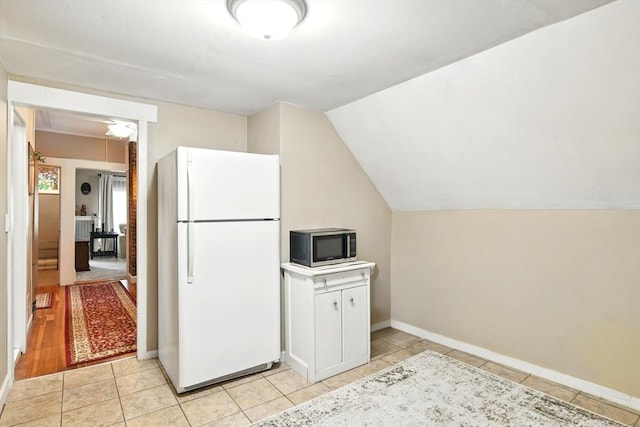 52 Harvard St, Chicopee, MA 01020 - kitchen with freestanding refrigerator, stainless steel microwave, light tile patterned floors, vaulted ceiling, and baseboards