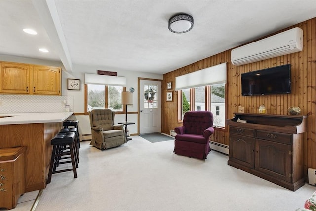 living area with light carpet, wooden walls, a wall mounted air conditioner, and a baseboard radiator