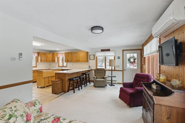 living area with light tile patterned floors, light colored carpet, an AC wall unit, and a healthy amount of sunlight