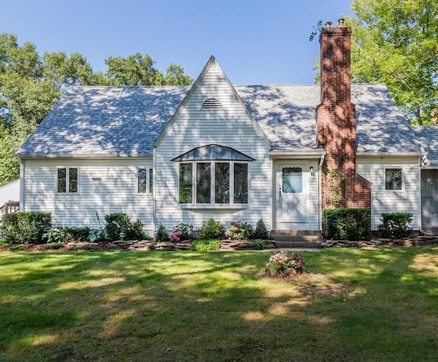 back of property with a shingled roof, a lawn, and a chimney