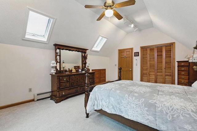 carpeted bedroom with track lighting, baseboards, ceiling fan, vaulted ceiling with skylight, and a baseboard radiator