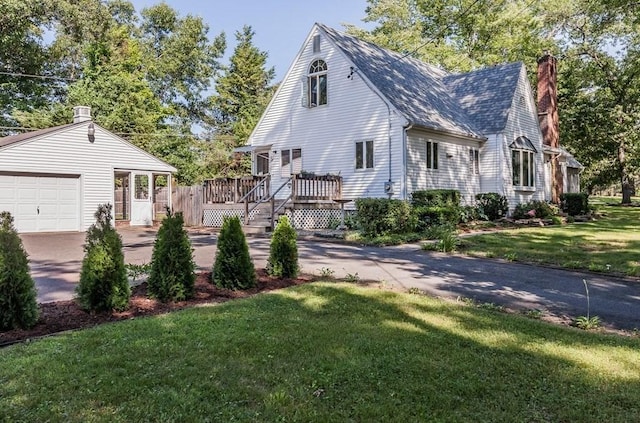 view of home's exterior with a deck, driveway, a yard, a garage, and a chimney