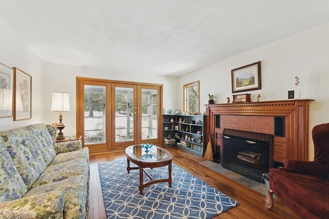 living room with a brick fireplace and wood finished floors