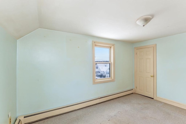 carpeted empty room with a baseboard heating unit and vaulted ceiling