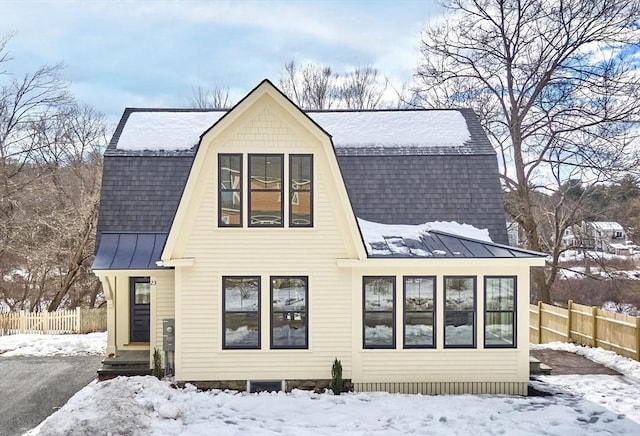 exterior space featuring a shingled roof, a gambrel roof, a standing seam roof, fence, and metal roof