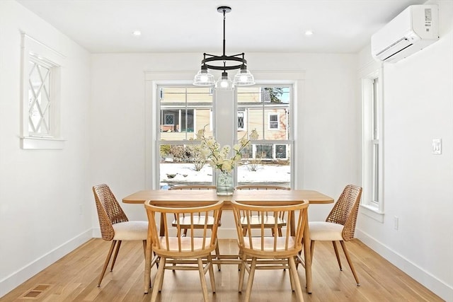 dining room with light wood-type flooring, a wall mounted air conditioner, visible vents, and baseboards