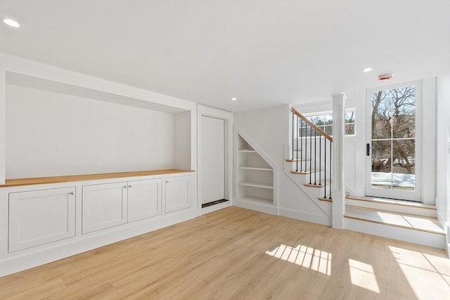 empty room with stairs, light wood finished floors, recessed lighting, and built in features