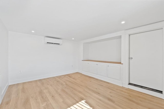 unfurnished room featuring baseboards, an AC wall unit, wood finished floors, and recessed lighting