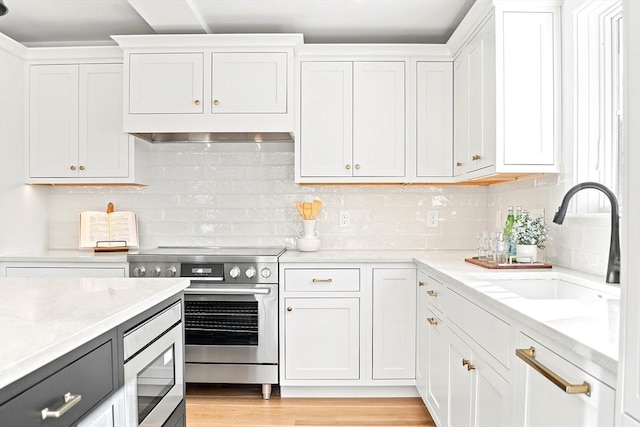 kitchen with stainless steel appliances, white cabinets, a sink, and tasteful backsplash