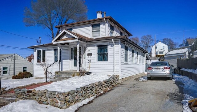 view of front of property featuring aphalt driveway, a chimney, and fence
