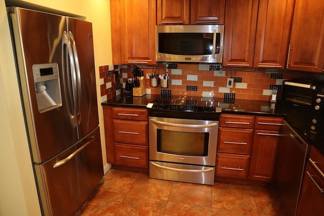 kitchen featuring dark stone countertops, decorative backsplash, tile patterned floors, and appliances with stainless steel finishes